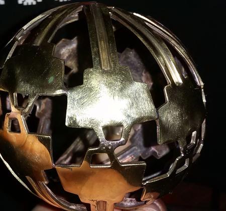 A dark sphere assembled from cut metal pieces